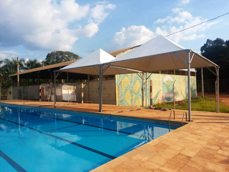A imagem mostra algumas tendas ao lado de uma piscina, preparadas para um evento esportivo.